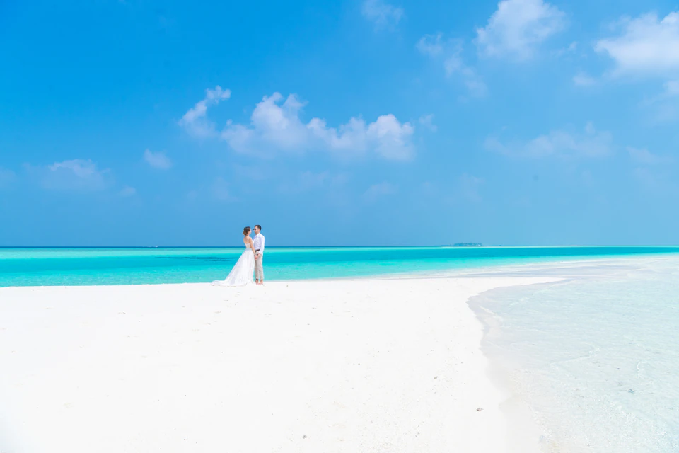 Wedding couple standing on a bright white sandbank