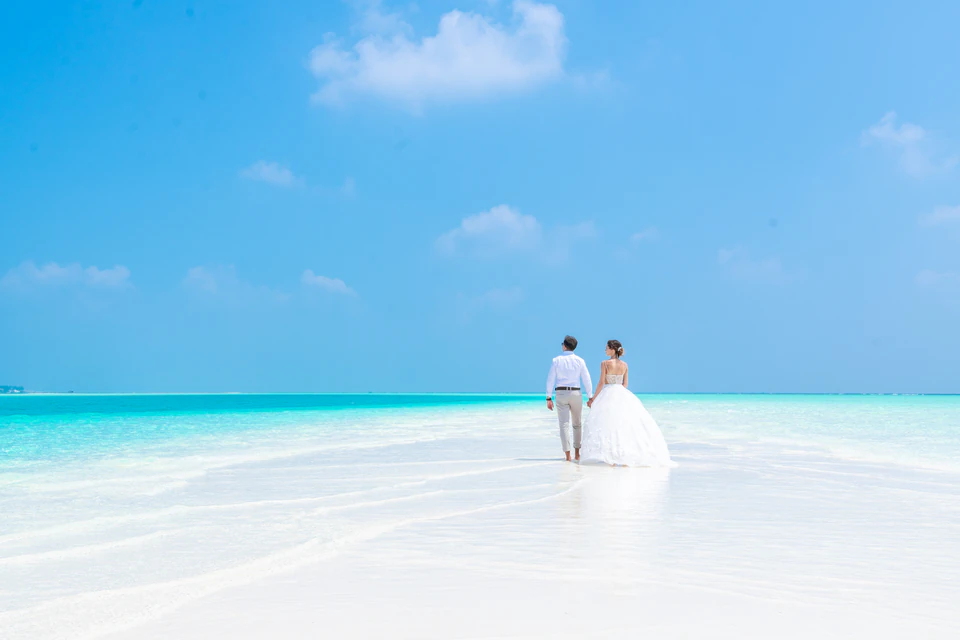 Wedding couple walking together along a white sandbank