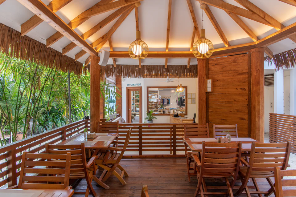 Covered wooden restaurant deck with dining tables and pendant lights