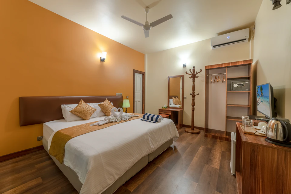 Wide view of the double bed, television, wardrobe, and refreshment counter