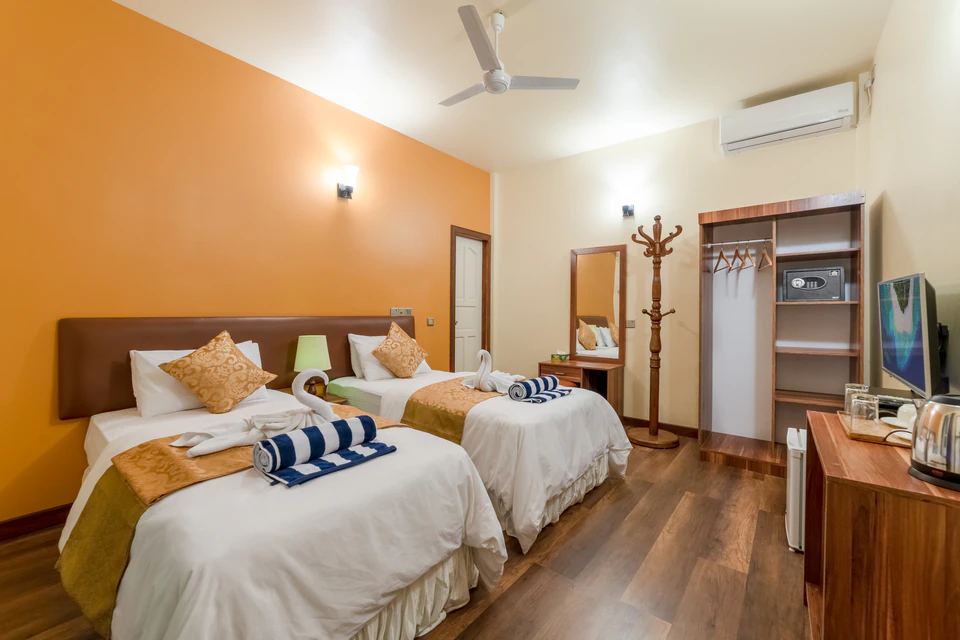 Wide twin-bed room view toward the wardrobe and television