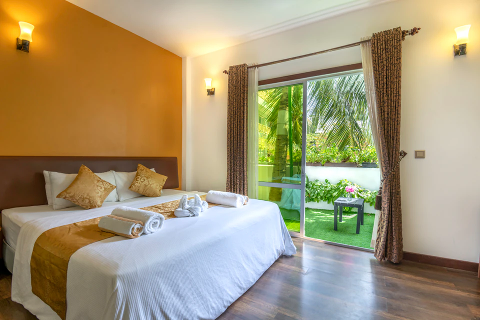 Double bed beside glass doors opening to a small ground-level patio